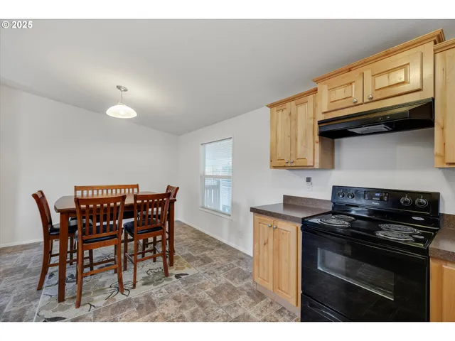 a kitchen with stainless steel appliances granite countertop a stove a sink a microwave and dining table