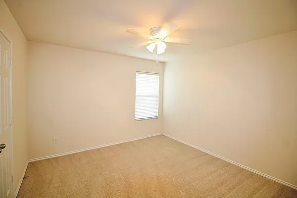 an empty room with a chandelier fan and windows