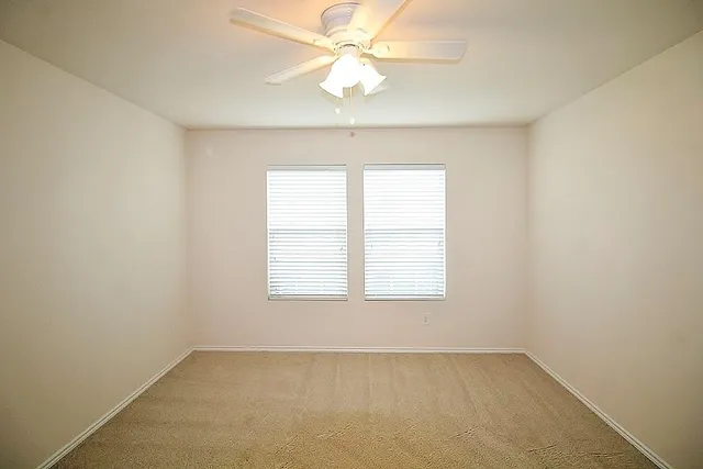 an empty room with a window and a fan