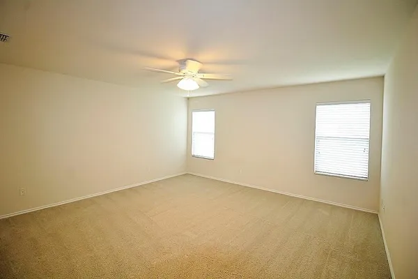 an empty room with windows and fan