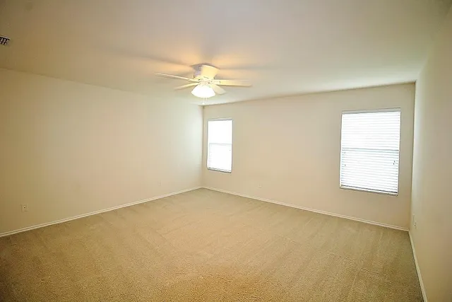 an empty room with windows and fan