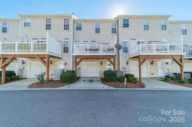 a front view of a building with garden and parking