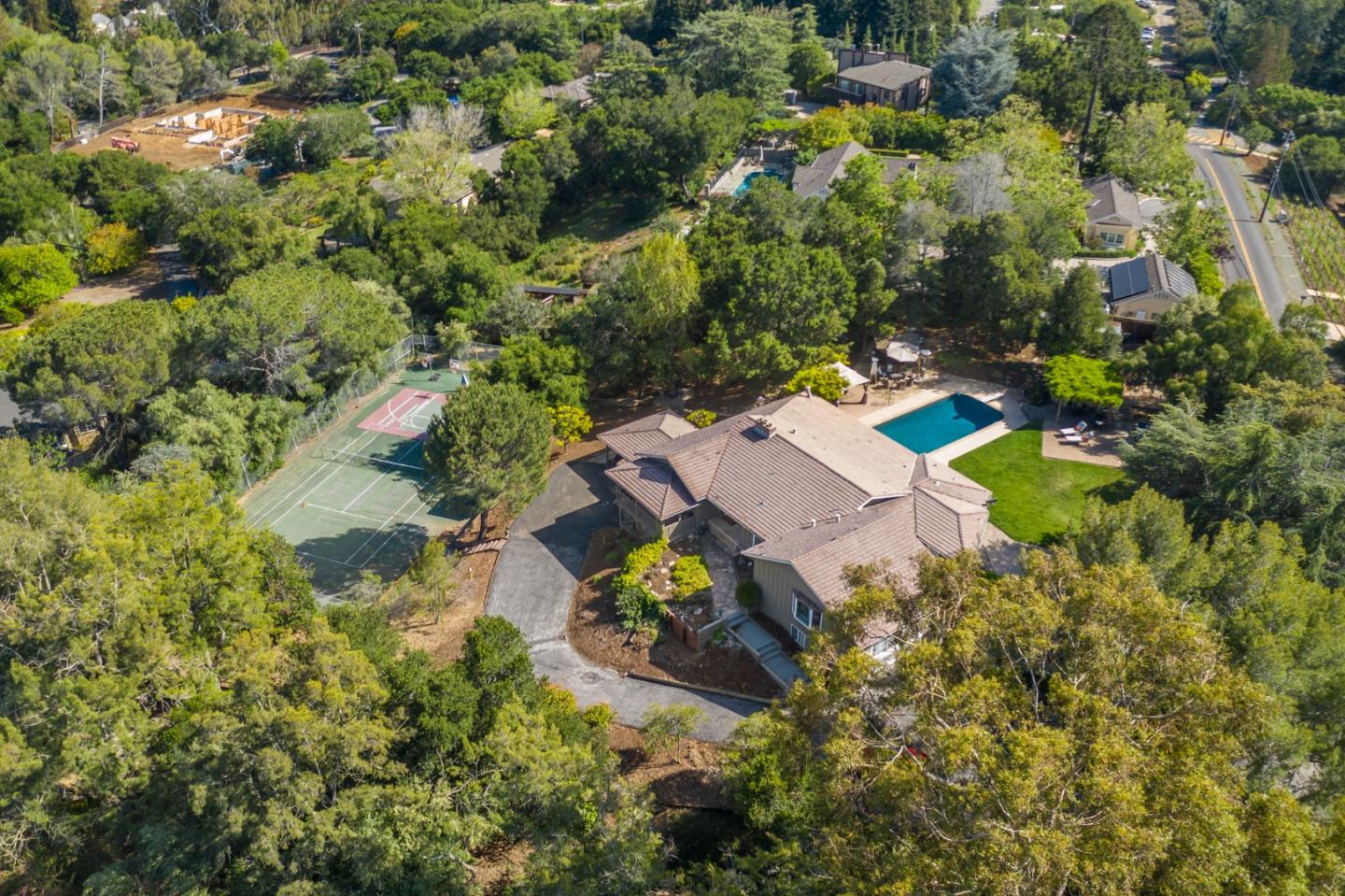 an aerial view of residential house with outdoor space and trees all around