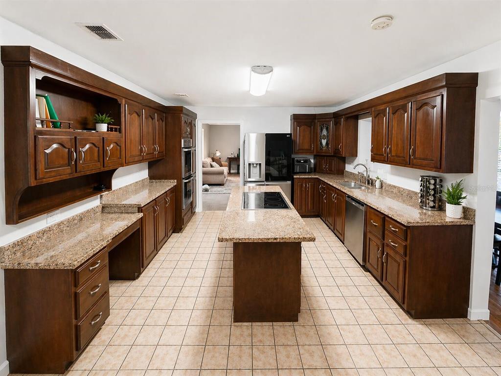 2313 Southeast 7th Street Ocala, FL 34471 - Photo 32 of 54 a large kitchen with kitchen island granite countertop a large counter top space a sink a window and stainless steel appliances