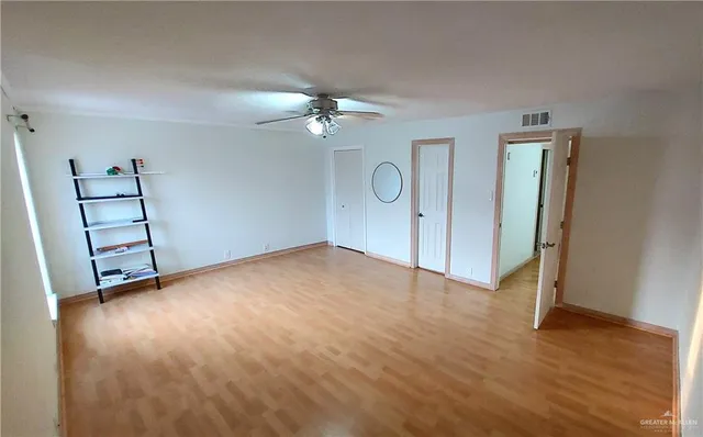 an empty room with wooden floor and ceiling fan