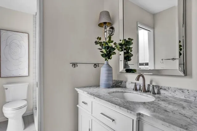 a bathroom with a granite countertop toilet sink and mirror