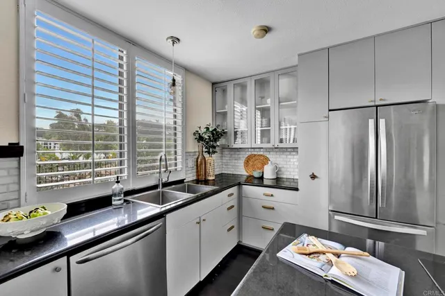 a kitchen with stainless steel appliances a sink a refrigerator a window and cabinets