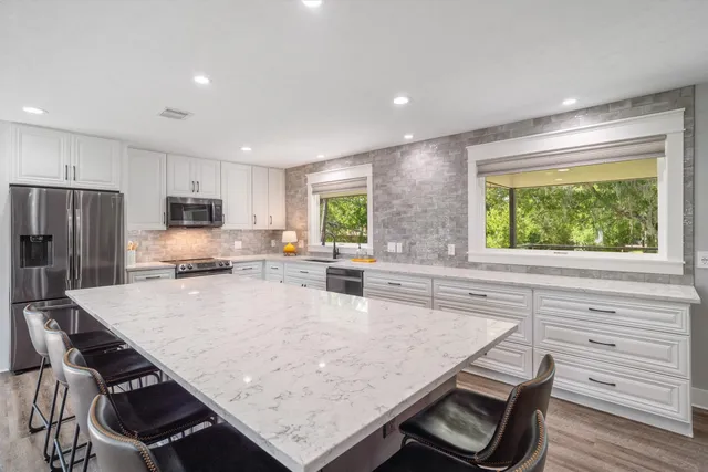 a kitchen with granite countertop a stove a sink a dining table and chairs