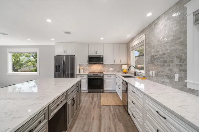 a large kitchen with stainless steel appliances granite countertop a lot of counter space and wooden floors