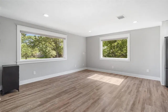 an empty room with wooden floor and windows