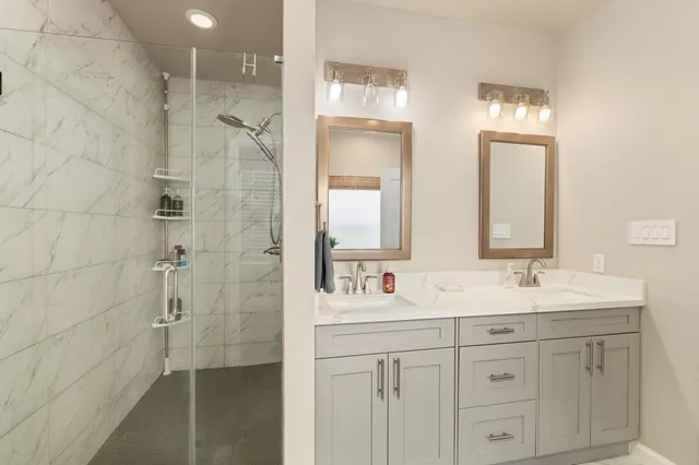 a bathroom with a double vanity sink mirror and shower