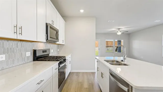 a kitchen with stainless steel appliances a sink a stove a microwave a sink a refrigerator and cabinets