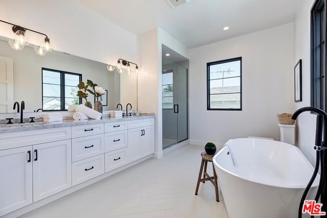 a bathroom with double vanity sink a two mirror a window and a bathtub
