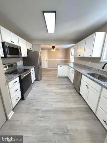 a large kitchen with cabinets wooden floor and stainless steel appliances