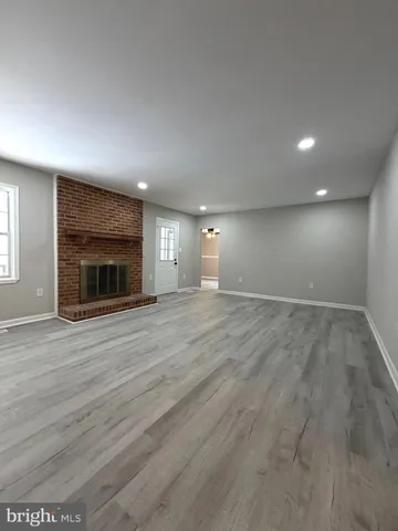 an empty room with wooden floor fireplace and windows