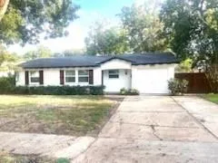 a view of a white house with a yard plants and large tree
