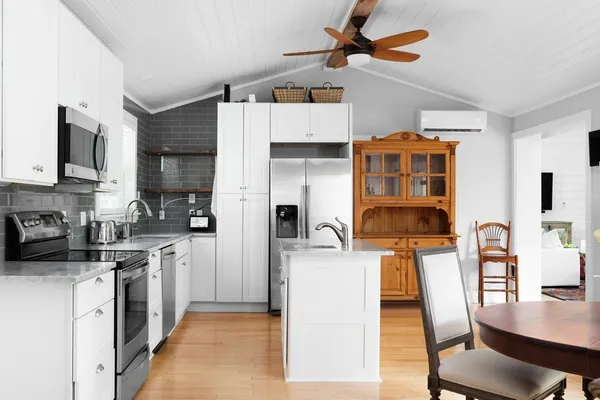 a kitchen with stainless steel appliances granite countertop a stove top oven a refrigerator a sink dishwasher and white cabinets with wooden floor