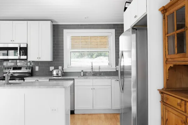 a kitchen with stainless steel appliances granite countertop a refrigerator a sink a stove and white cabinets