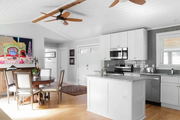 a kitchen with stainless steel appliances kitchen island granite countertop a dining table chairs refrigerator and sink