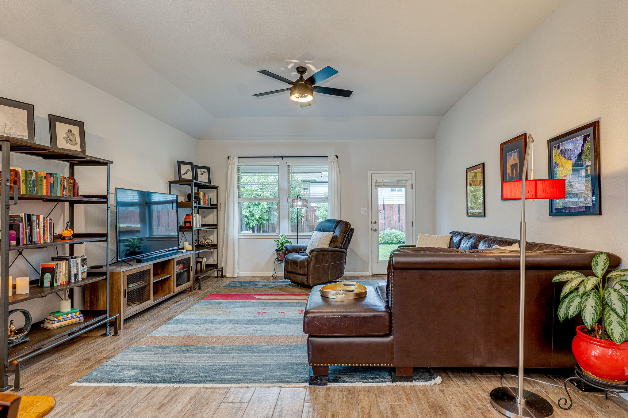 1009 Goldilocks Lane Manchaca, TX 78652 - Photo 13 of 40 Living area featuring wood-look tile flooring, a ceiling fan with integrated lighting, and multiple windows with 2" faux wood blinds.