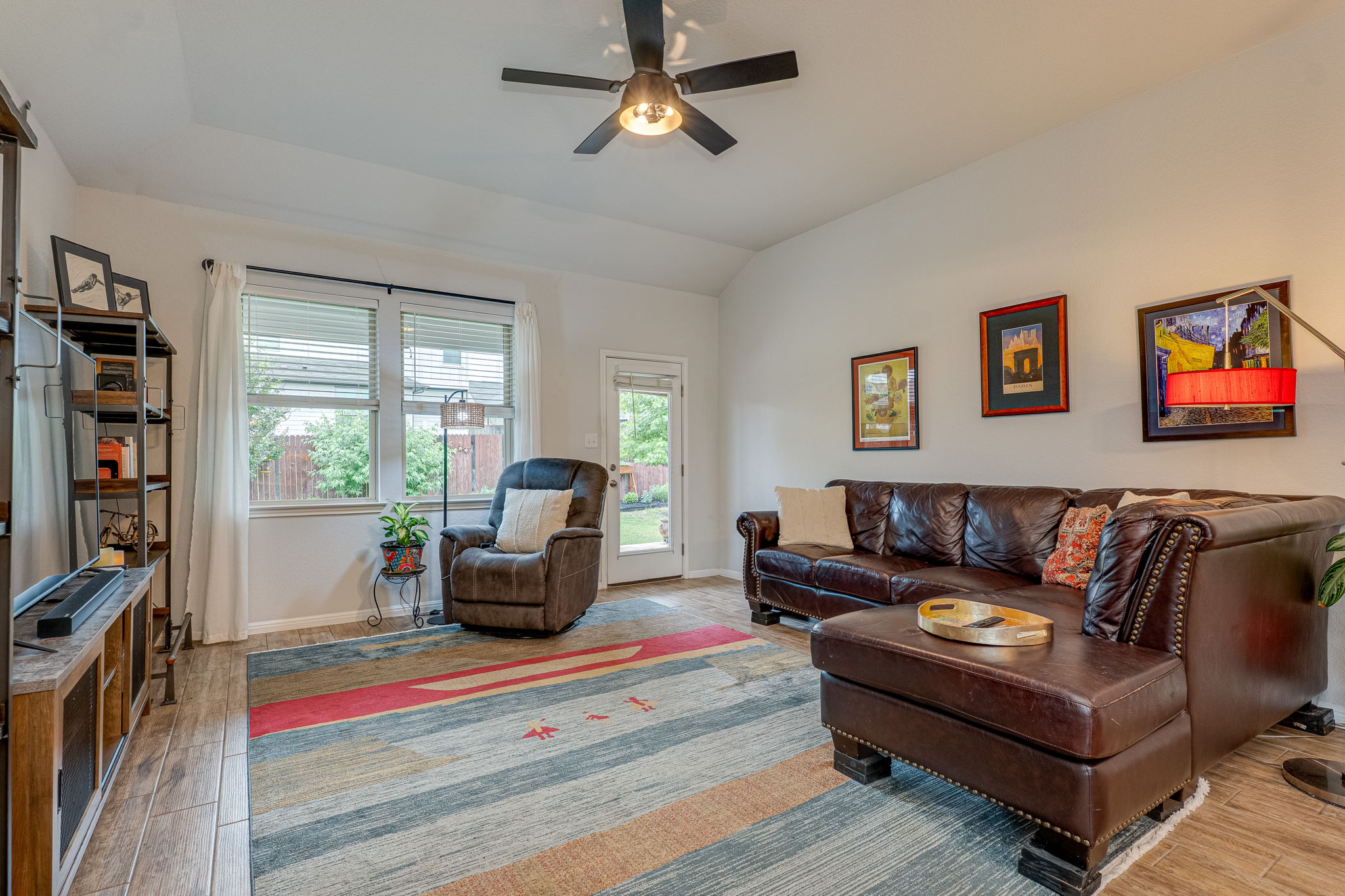 1009 Goldilocks Lane Manchaca, TX 78652 - Photo 14 of 40 Living area featuring wood-look tile flooring, a ceiling fan with integrated lighting, and multiple windows with 2" faux wood blinds.