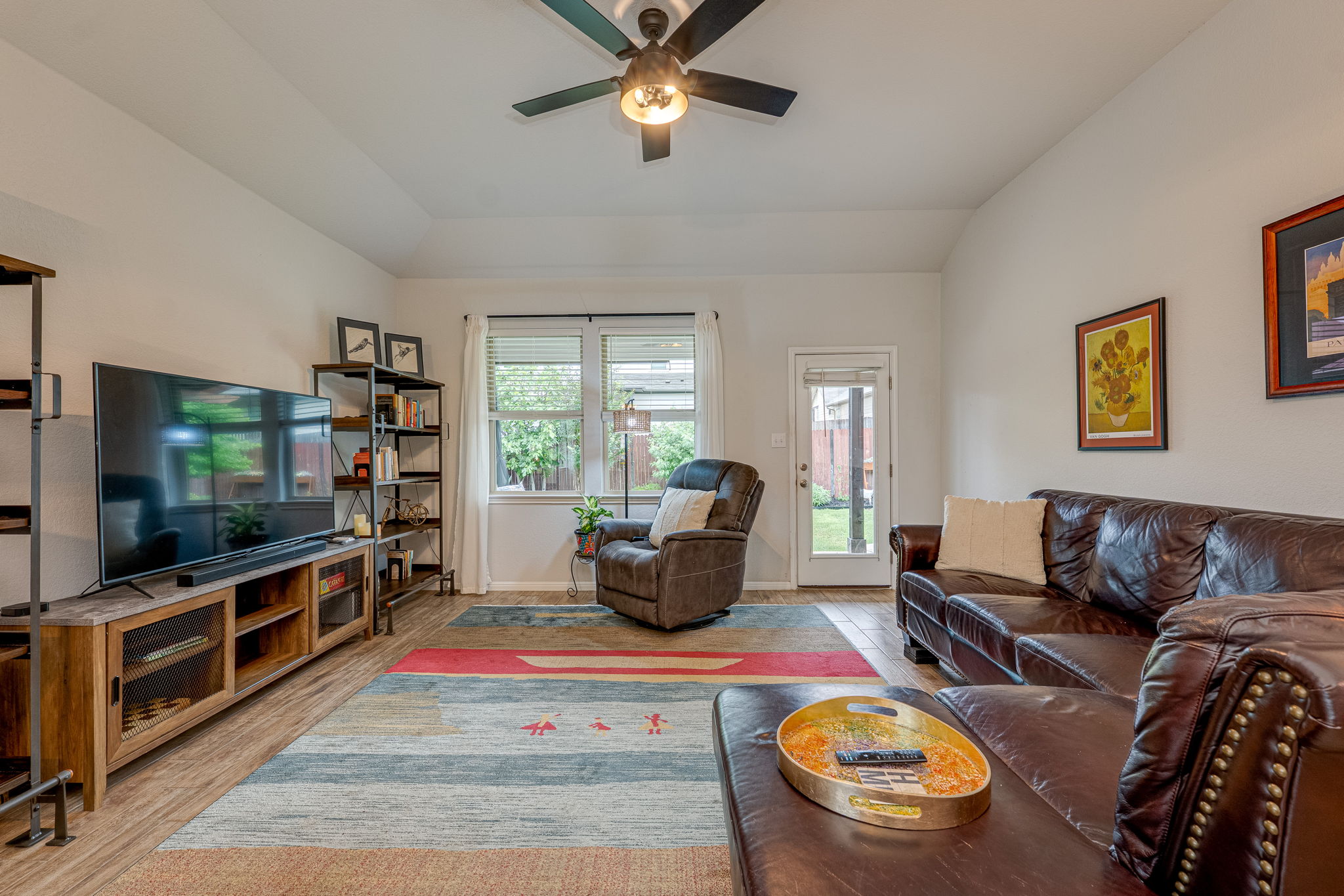 1009 Goldilocks Lane Manchaca, TX 78652 - Photo 15 of 40 Living area featuring wood-look tile flooring, a ceiling fan with integrated lighting, and multiple windows with 2" faux wood blinds.