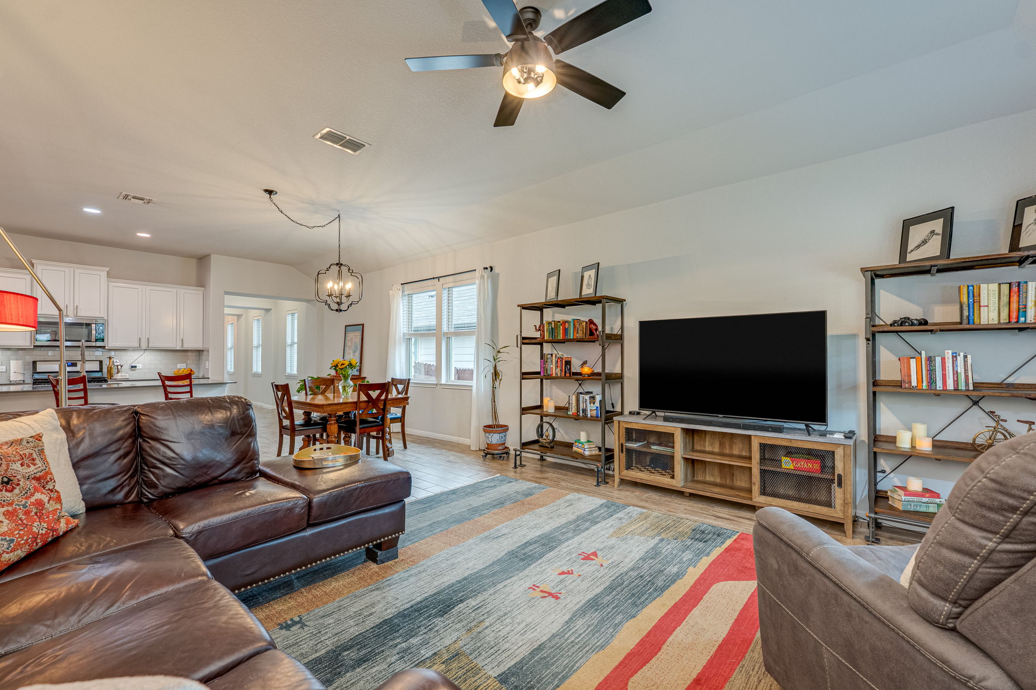 1009 Goldilocks Lane Manchaca, TX 78652 - Photo 16 of 40 Living area featuring wood-look tile flooring, a ceiling fan with integrated lighting, and multiple windows with 2" faux wood blinds.