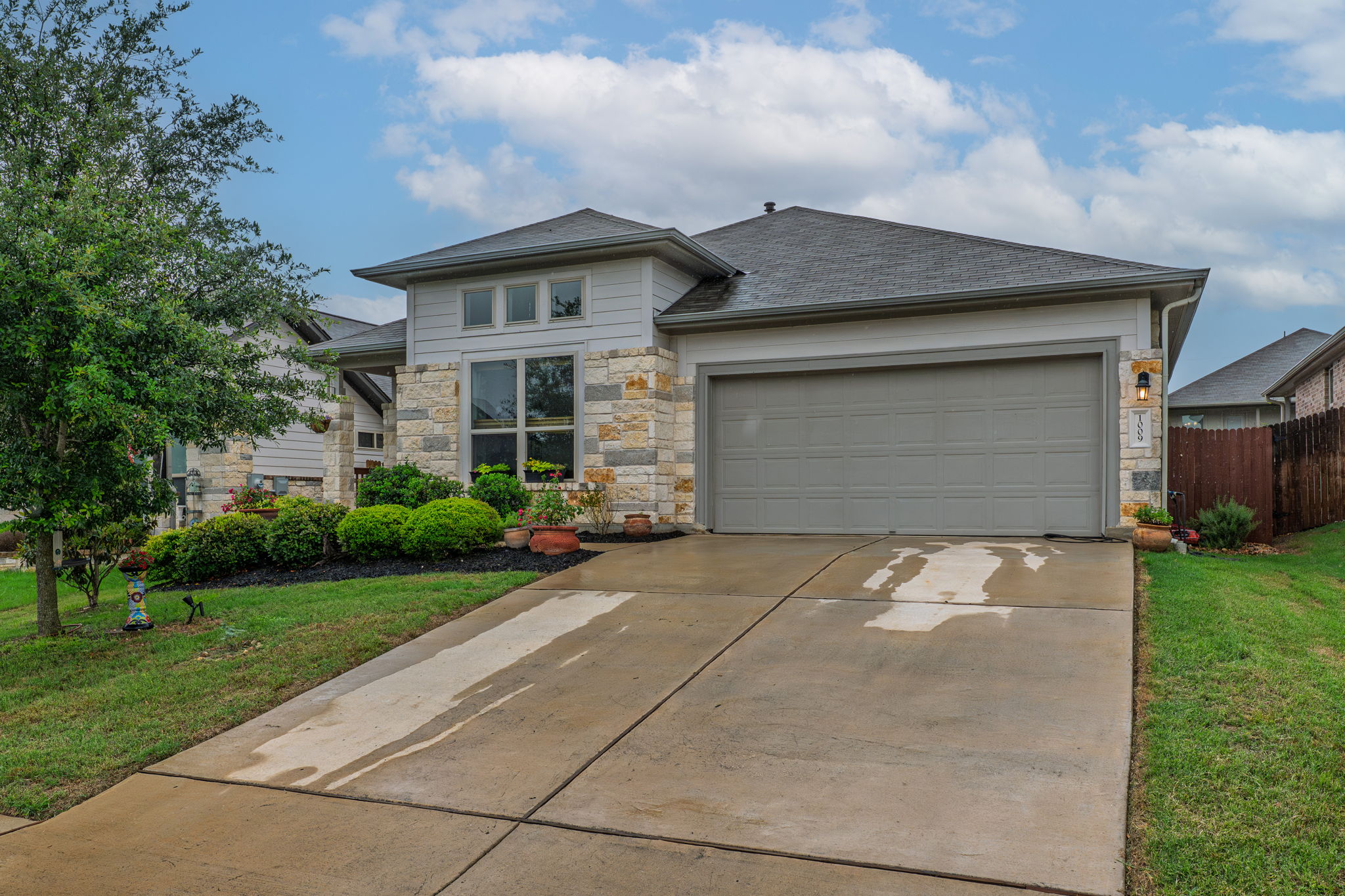 1009 Goldilocks Lane Manchaca, TX 78652 - Photo 2 of 40 Contemporary-style single-story home featuring a stone and siding facade, an attached two-car garage, and a concrete driveway.