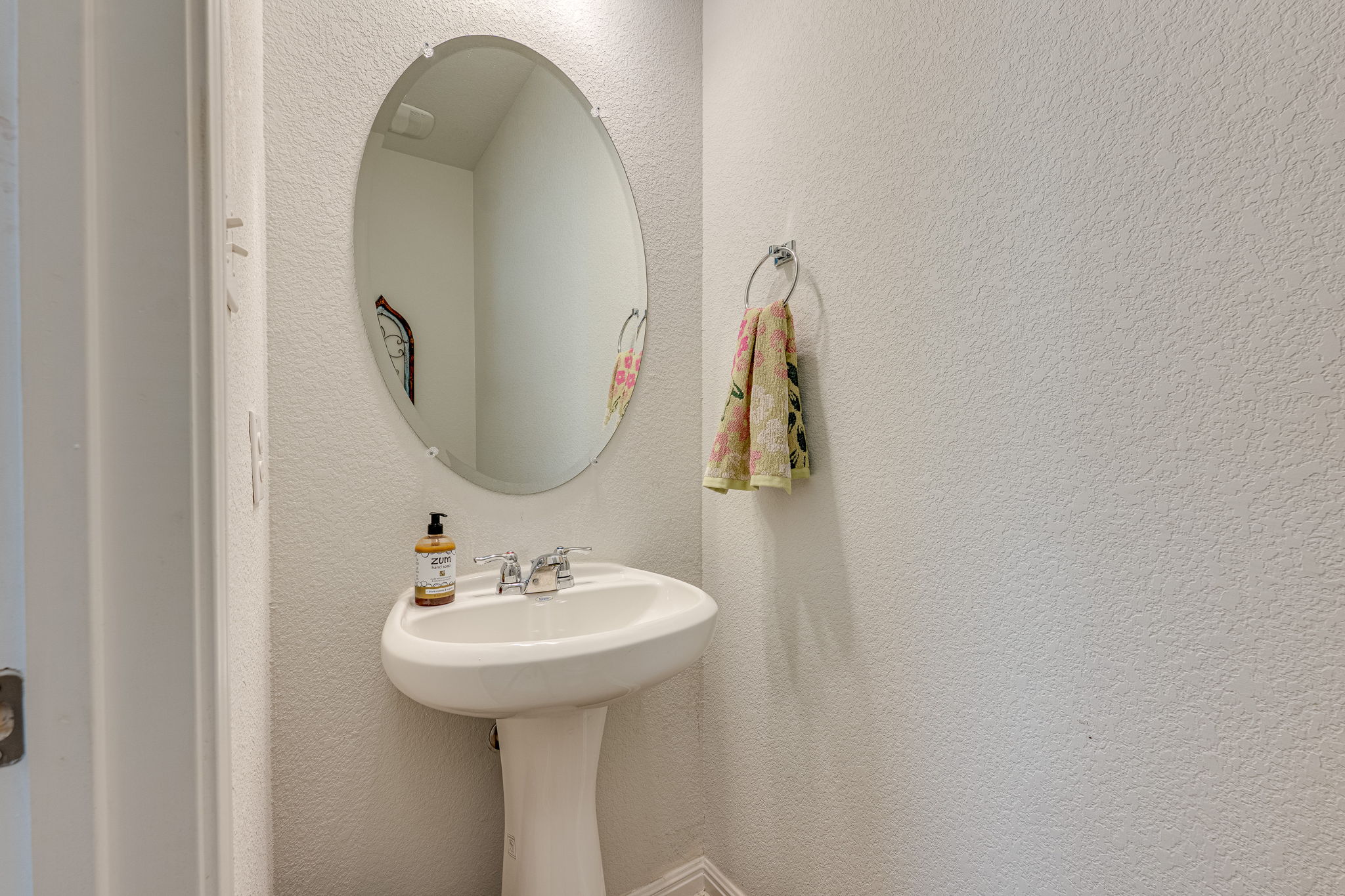 1009 Goldilocks Lane Manchaca, TX 78652 - Photo 30 of 40 Powder room located in the hallway near the entry. Pedestal sink with chrome fixtures and an oval, frameless mirror.