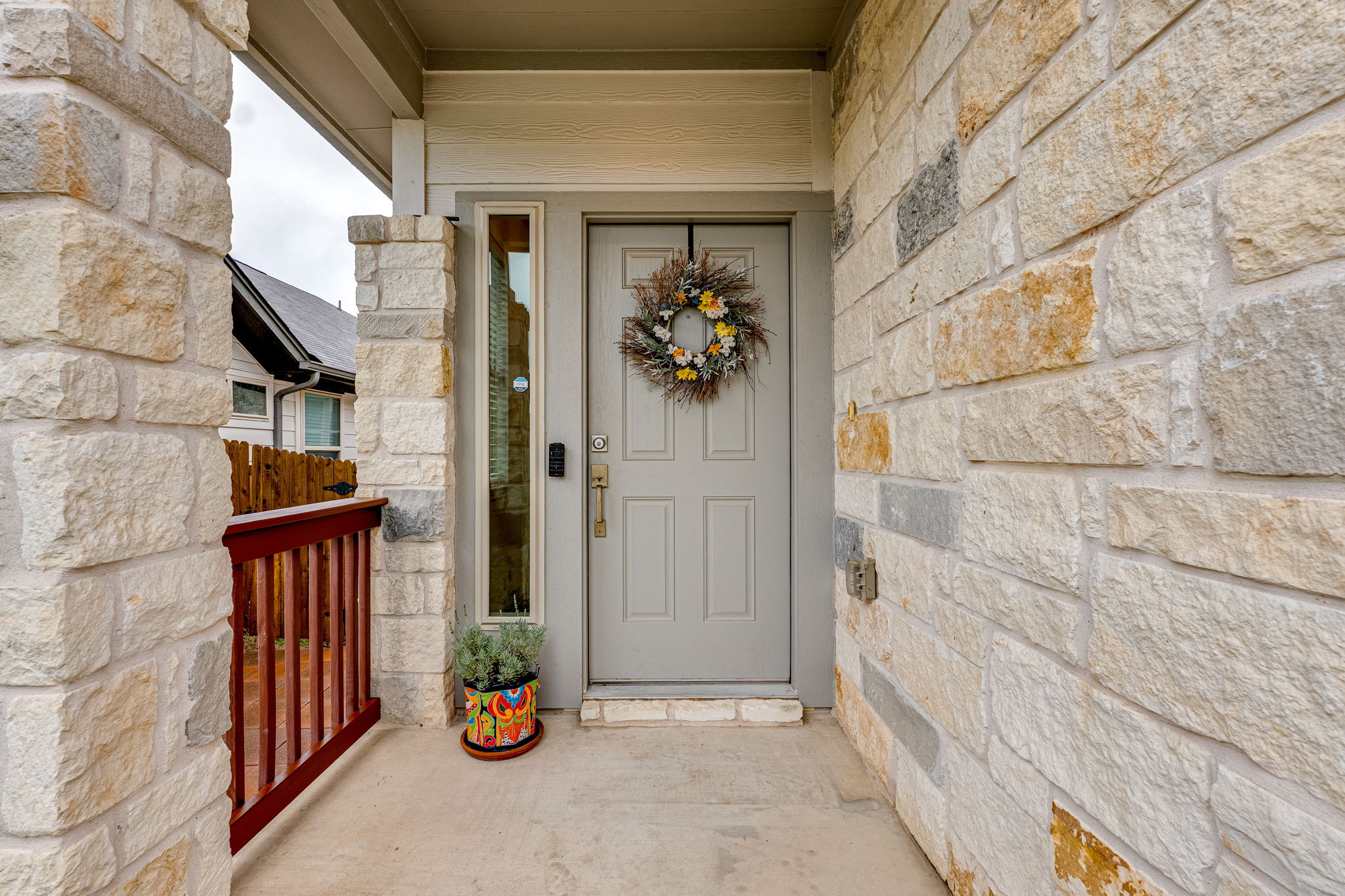 1009 Goldilocks Lane Manchaca, TX 78652 - Photo 3 of 40 Stone veneer exterior with a paneled entry door, sidelight window, and concrete porch flooring.
