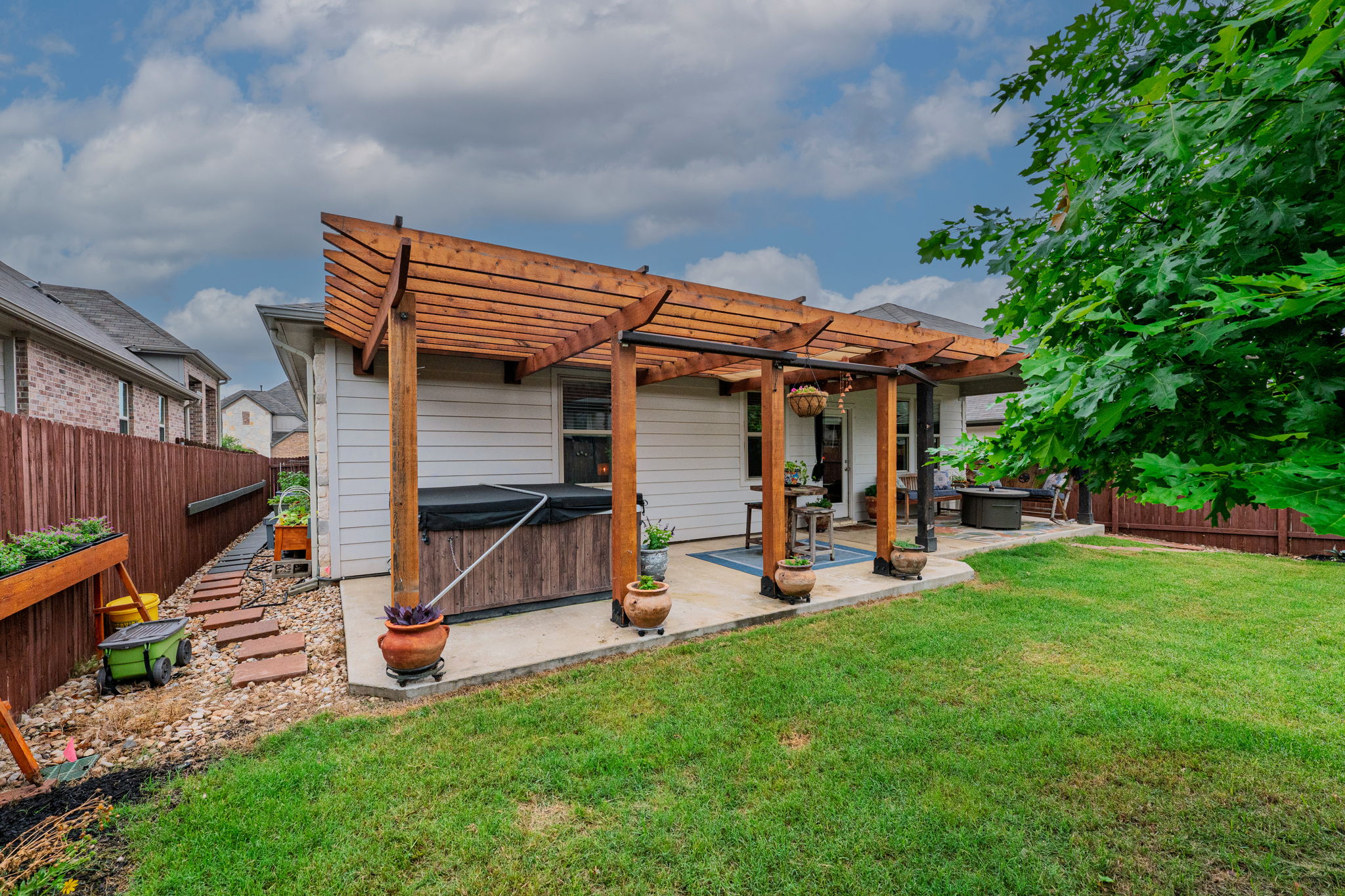 1009 Goldilocks Lane Manchaca, TX 78652 - Photo 32 of 40 Backyard patio featuring a wood pergola, concrete slab, and an adjacent stone pathway leading to the front.