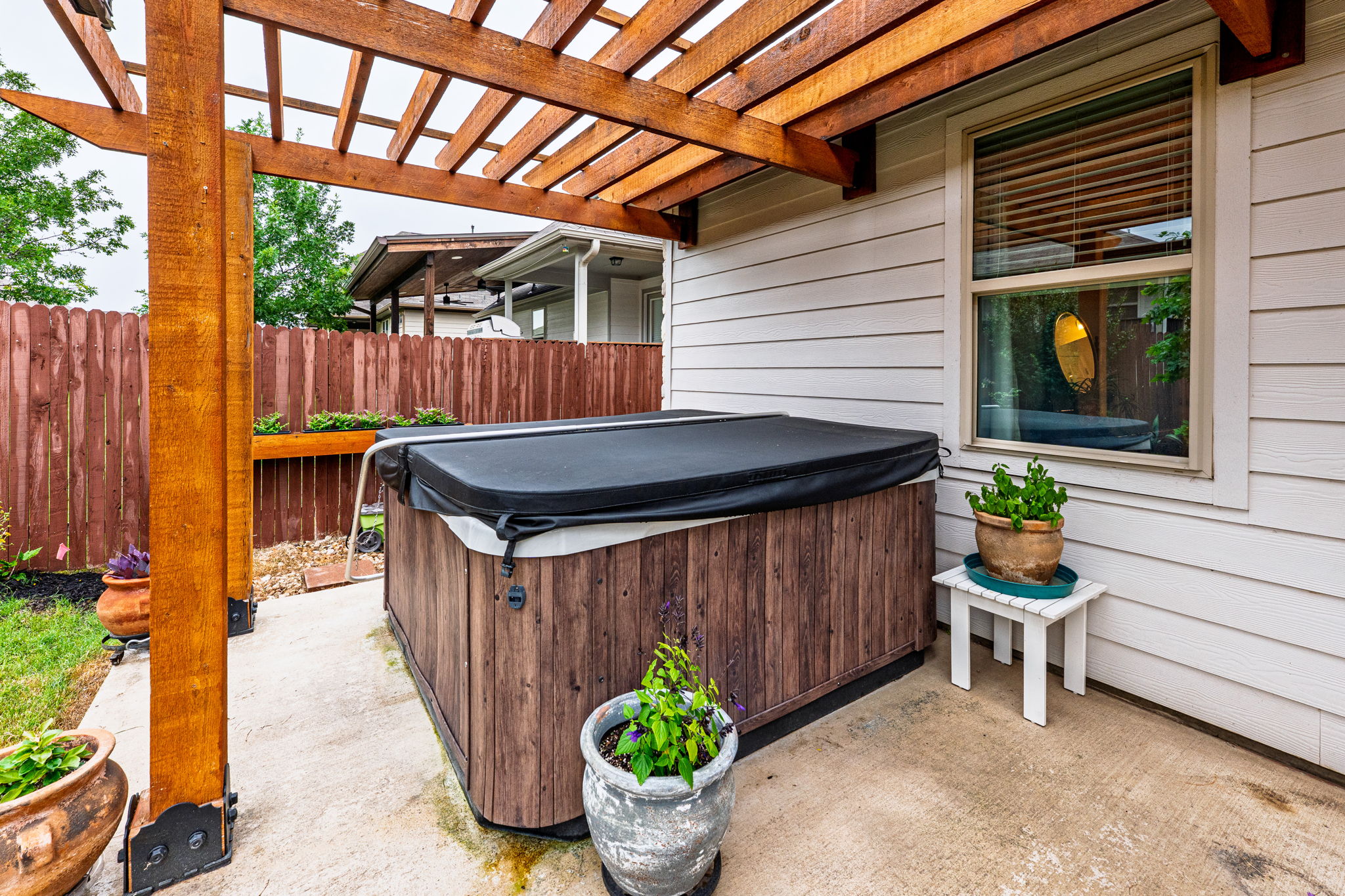 1009 Goldilocks Lane Manchaca, TX 78652 - Photo 33 of 40 Outdoor spa area featuring a wooden pergola, concrete patio, privacy fencing, and exterior siding.
