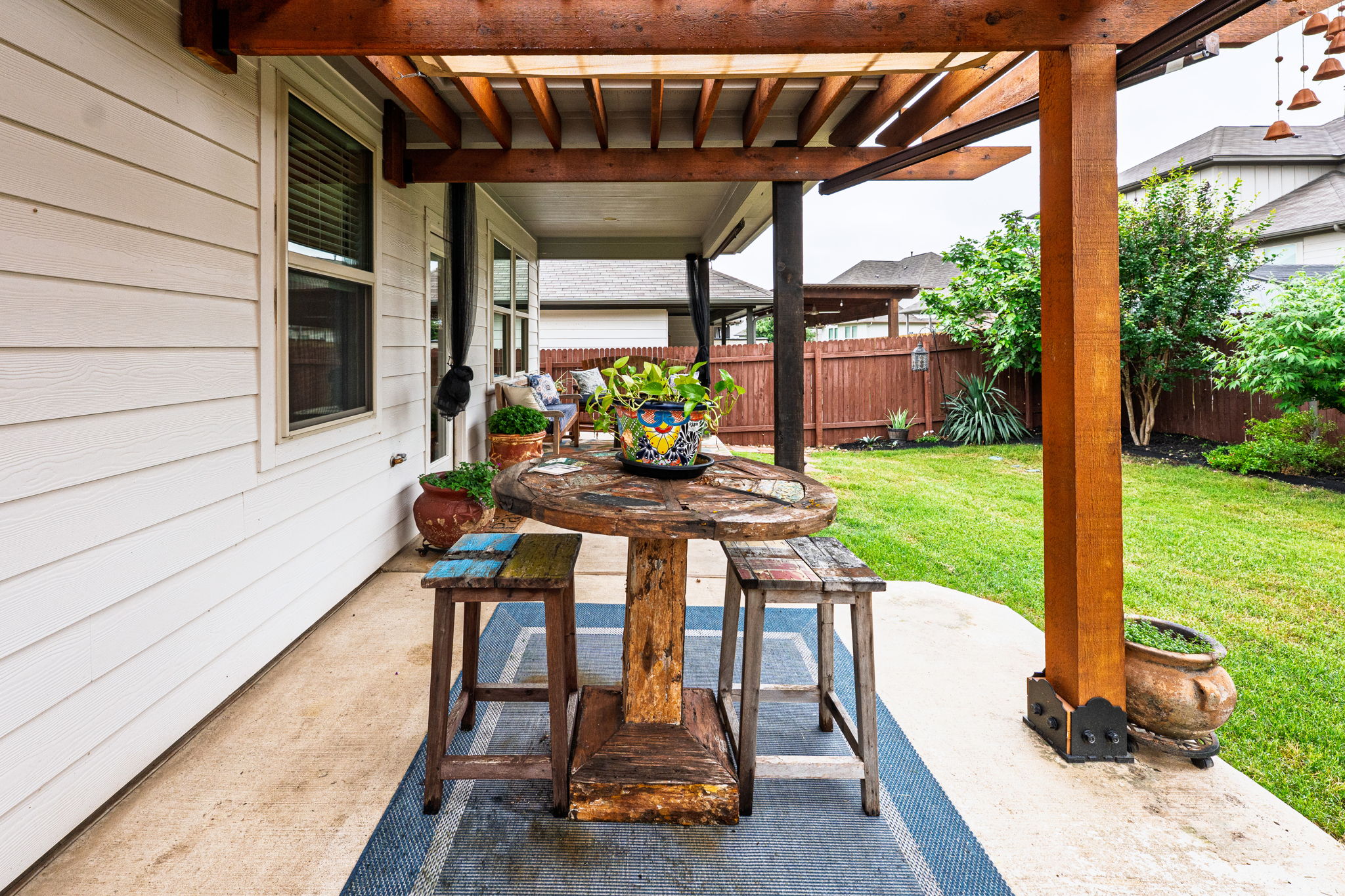 1009 Goldilocks Lane Manchaca, TX 78652 - Photo 35 of 40 Covered patio featuring a wood pergola structure, concrete flooring, and a manicured lawn.