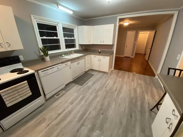 a kitchen with a sink wooden cabinets and a stove