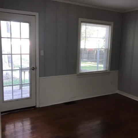 a view of an empty room and wooden floor and windows
