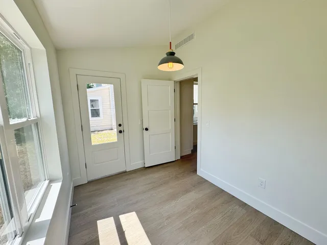 an empty room with wooden floor and windows