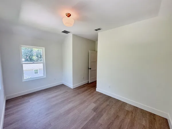 an empty room with wooden floor and ceiling fan