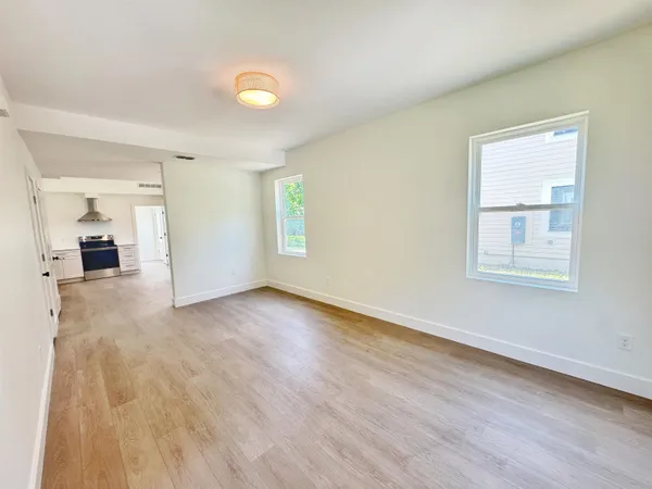 an empty room with wooden floor and windows