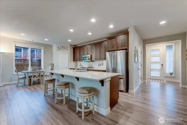 an open kitchen with wooden floor and refrigerator