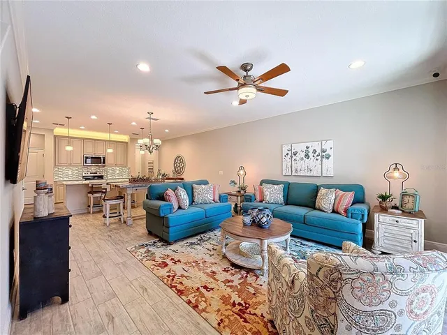 a living room with furniture kitchen view and a chandelier