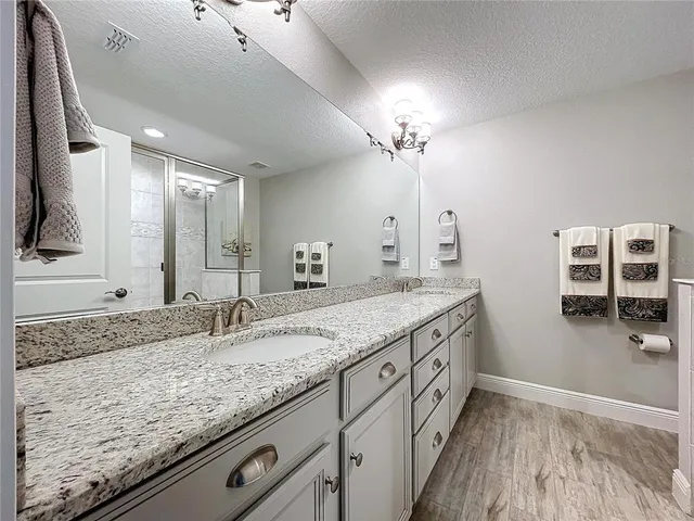 a bathroom with a granite countertop double vanity sink and a mirror