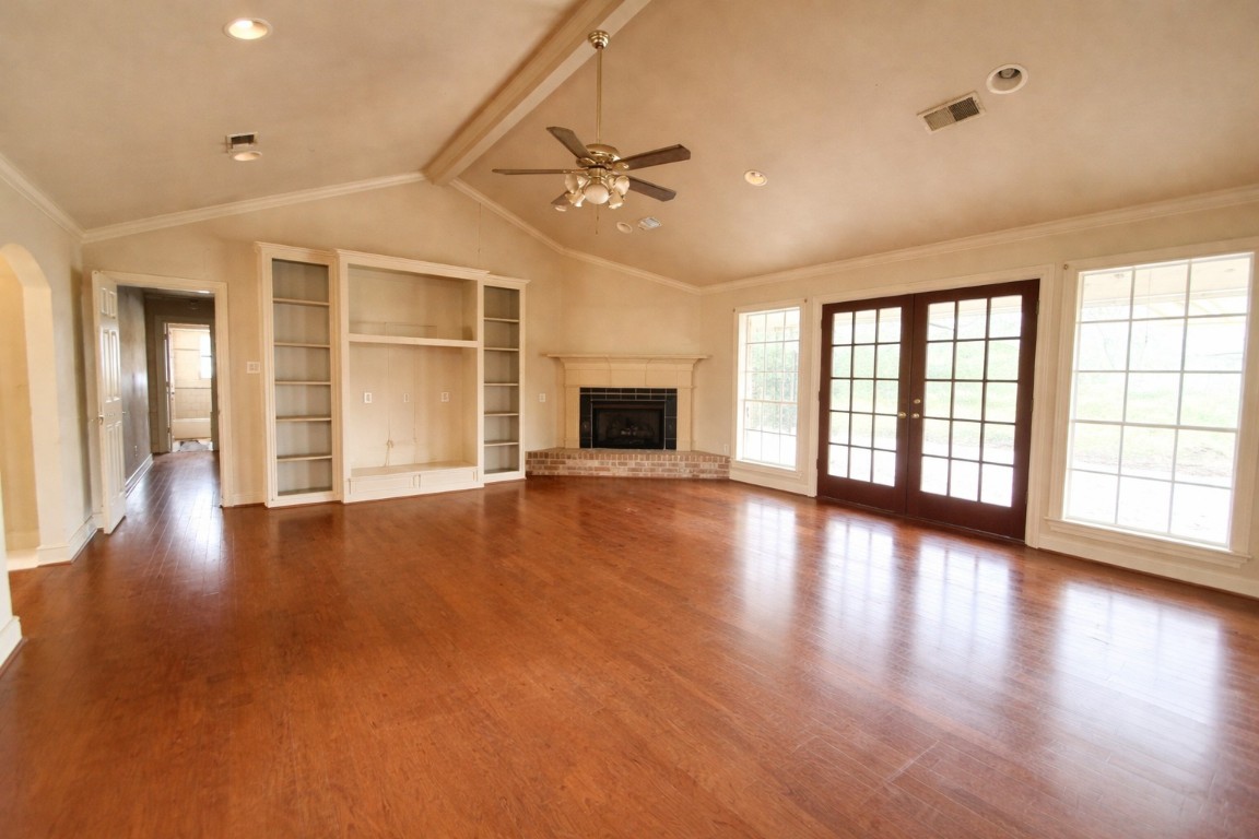 an empty room with floor to ceiling windows and fireplace
