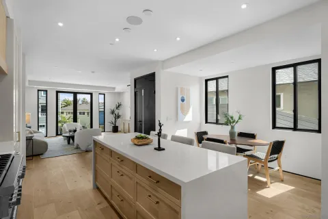 a kitchen with a stove a refrigerator and white cabinets with wooden floor