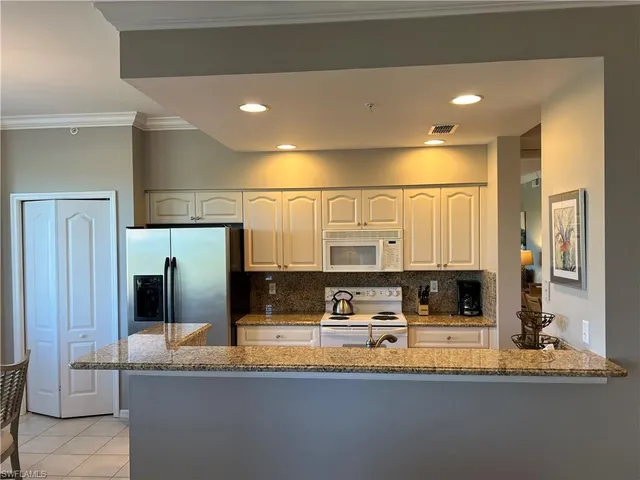a kitchen with stainless steel appliances granite countertop a sink and a refrigerator