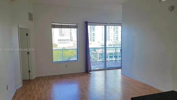 a view of an empty room with wooden floor and a window