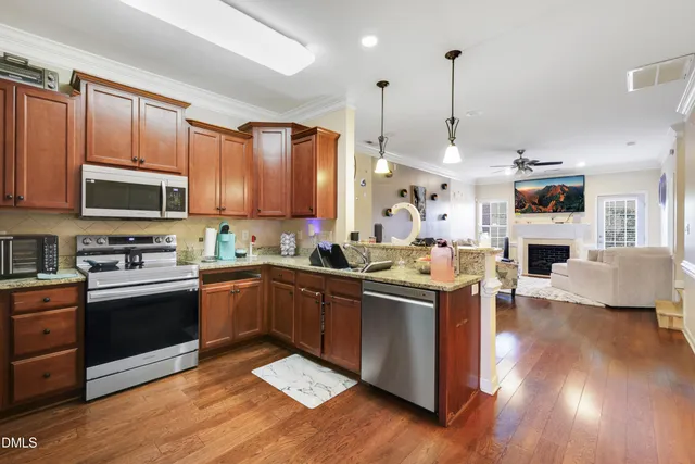 a kitchen with stainless steel appliances granite countertop a refrigerator a stove top oven a sink and dishwasher with wooden floor