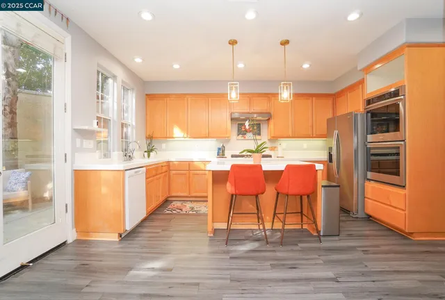 a kitchen with stainless steel appliances kitchen island granite countertop a table chairs and a refrigerator