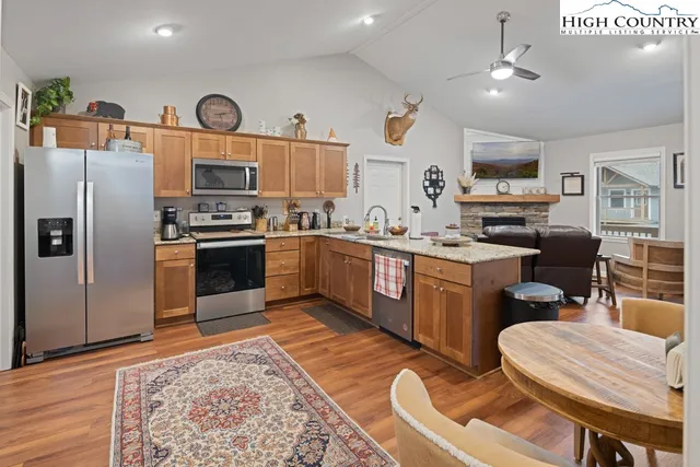 a kitchen with stainless steel appliances granite countertop a sink a stove a refrigerator cabinets and dining table
