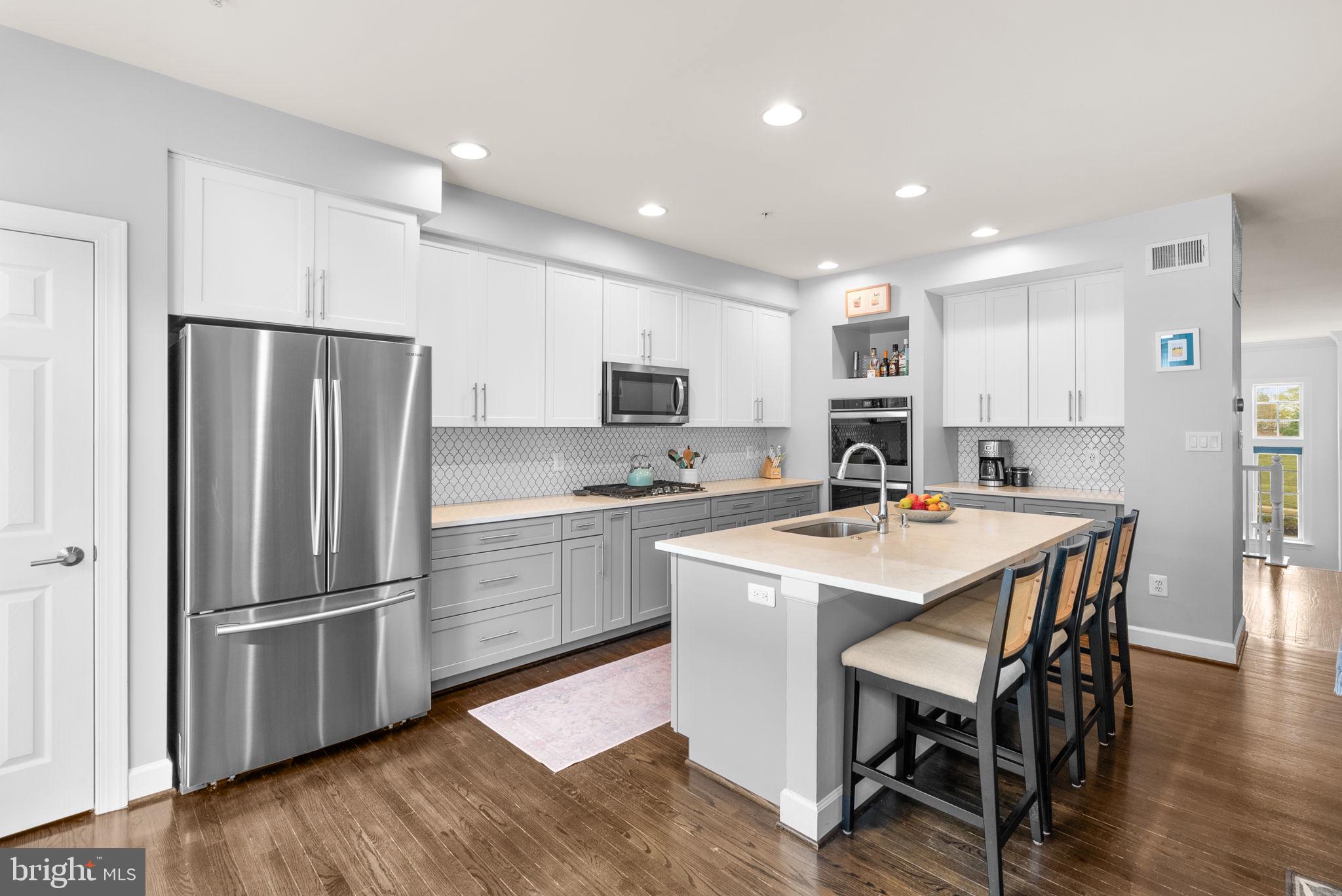 1222 Gaither Road Rockville, MD 20850 - Photo 10 of 42 a kitchen with a refrigerator a sink and a stove top oven with wooden floor