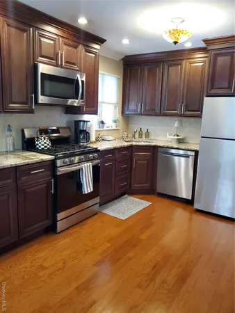 a kitchen with stainless steel appliances granite countertop a stove top oven a sink dishwasher and a microwave oven on the blue kitchen countertops